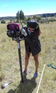 Gabby Joice driving a soil core with a petrol hammer to take samples at UNE