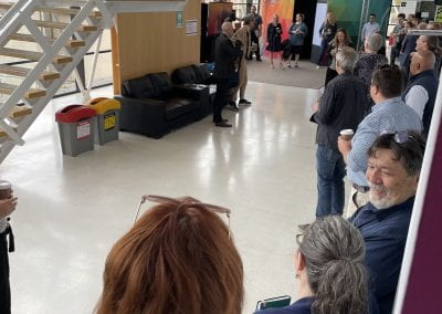 A crowd of people standing in the foyer of the TDS buidling. Steve Warburton is speaking to the crowd and the Igloo can be seen in the background.
