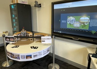 A physical scale model of the Globe Theatre is displayed on a table with various information on signs nearby. Next to it an interactive module using a 3D scan of the Globe Theatre model is displayed on a touch screen.