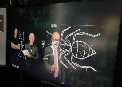 Mike Wilmore, Steve Warburton and Michael Partridge are in the Lightboard room - the photo is taken of the display monitor where an overlay image of an insect is being projected.