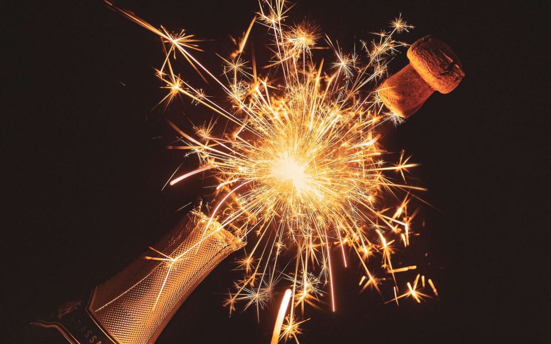 A cork popping out of a champagne bottle with a sparkler effect