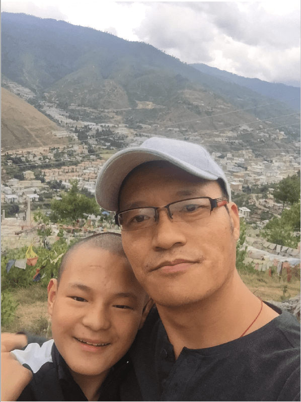 Karma Jigyel and his son with a backdrop of a Bhutan valley