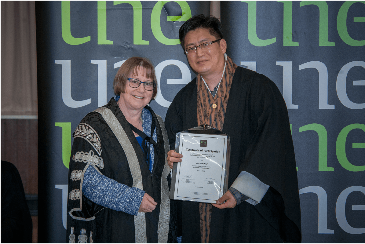 University of New England (UNE) Vice-Chancellor Annabelle Duncan presents Rinchen Dorji with a certificate of recognition for his UNE studies