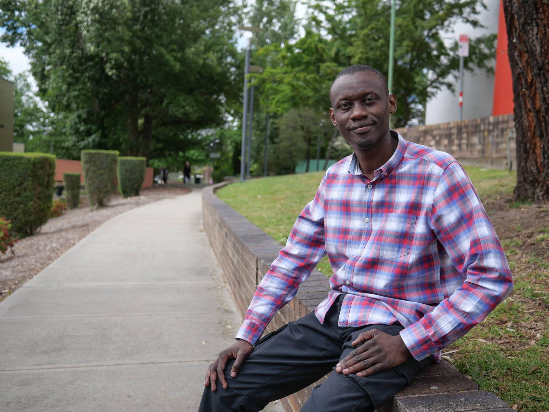 John Ahere, from Kenya, in a casual pose in the grounds of UNE.