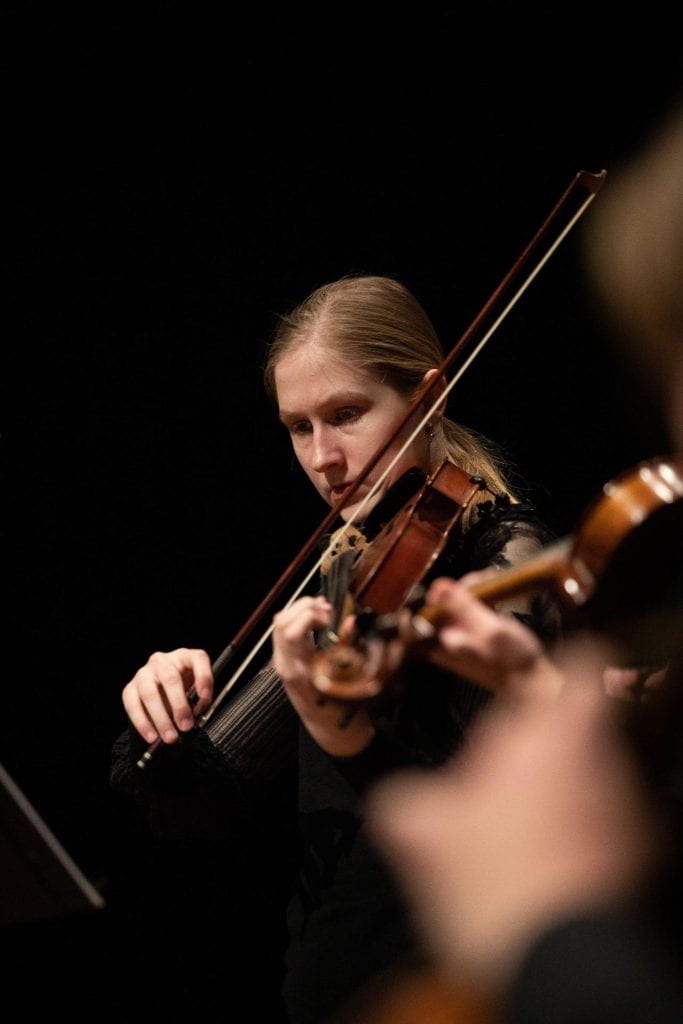 Portrait image of Bachelor of Music student Caitlin Annesley playing the violin with an orchestra