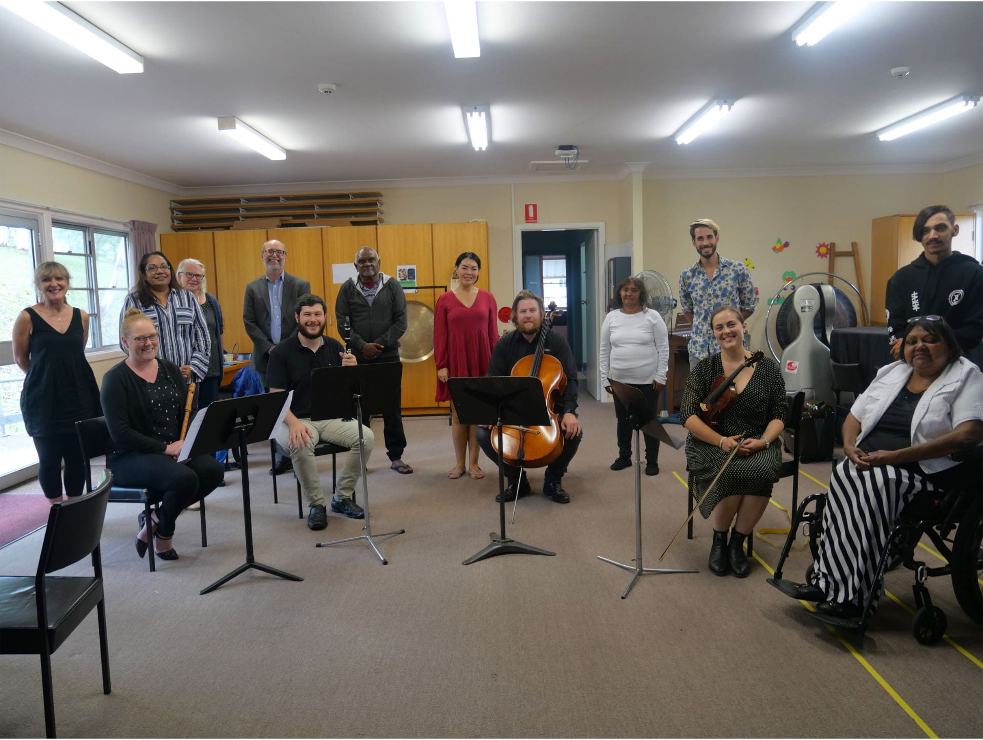 A group of individuals including the composition band, various members of UNE staff and Elder's from the local community stand together
