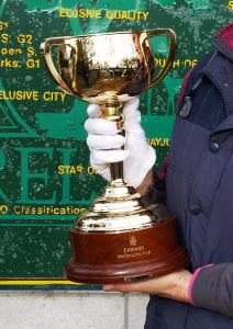 Close-up image of a white-gloved hand holding a large trophy cup.