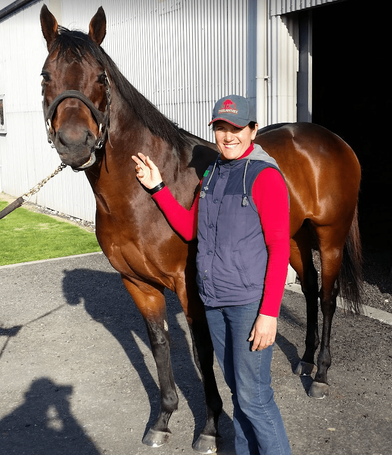 Francesca Brady standing next to a bay-coloured racehorse