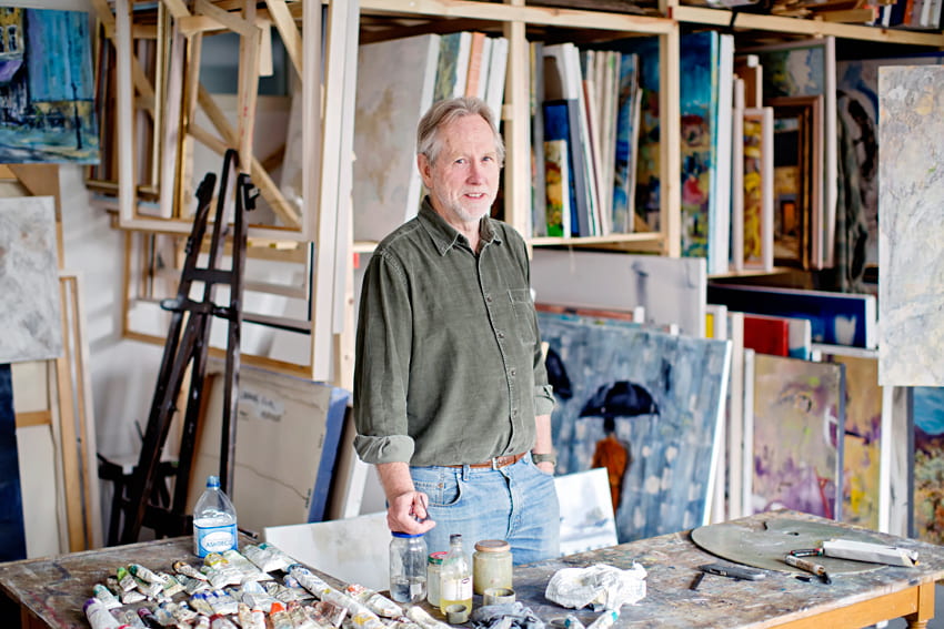 Artist Graham McBride surrounded by the tools of his trade - paint, canvases, easels and brushes in his studio