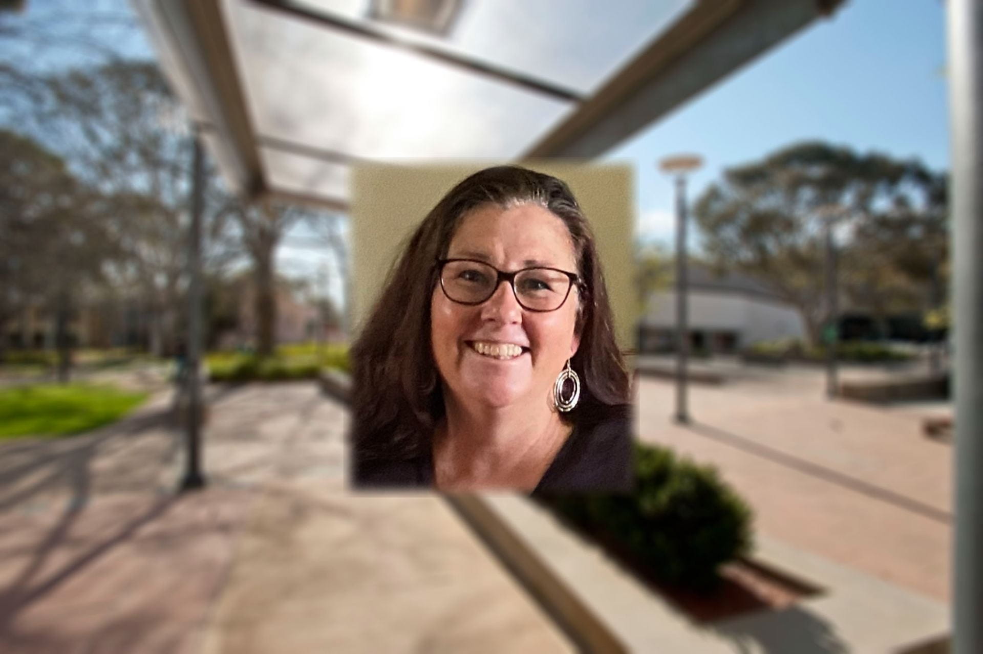 Portrait image of UNE Sue Smith against a blurred background of a university setting