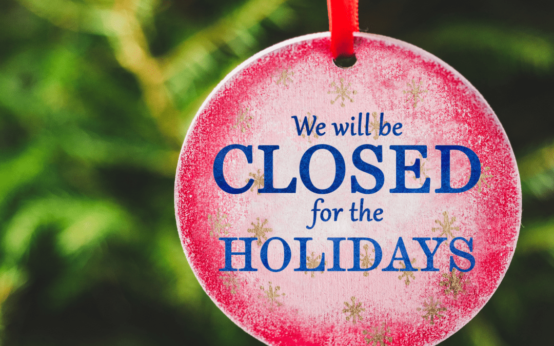 Red bauble with text 'We will be CLOSED for the HOLIDAYS' in front of a green, pine tree background.