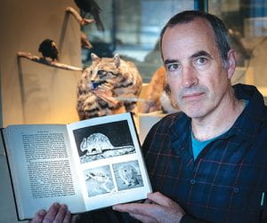 Associate Professor Karl Vernes holding up an opened book about the desert-rat-kangaroo.