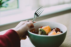 Bowl of healthy food, with a hand holding a fork.